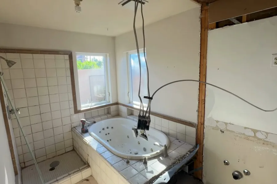 Bathroom wall opened for plumbing demolition during a plumbing service call in Gilbert, AZ