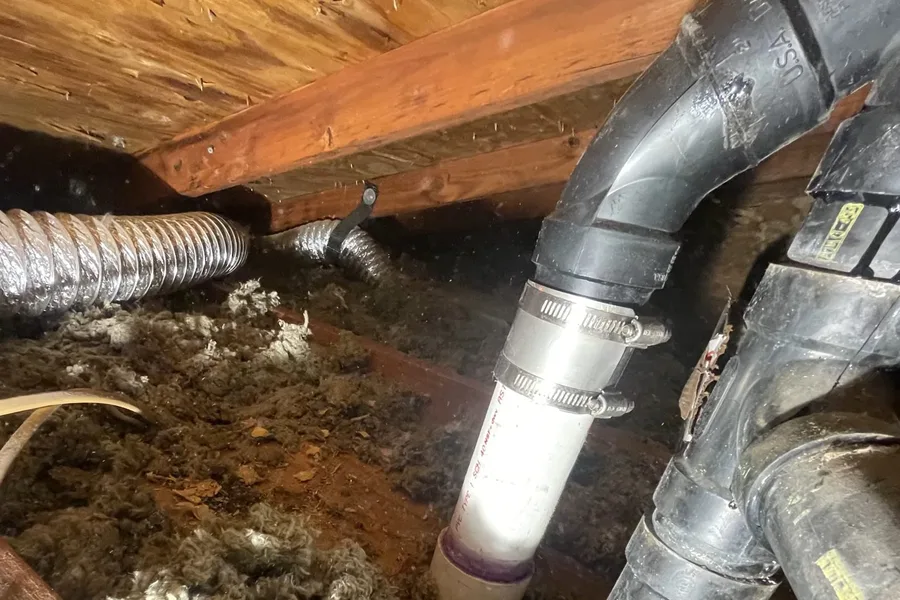 Black drain pipe with a flexible connector under framing during a plumbing service call in Fountain Park Area, Fountain Hills, AZ