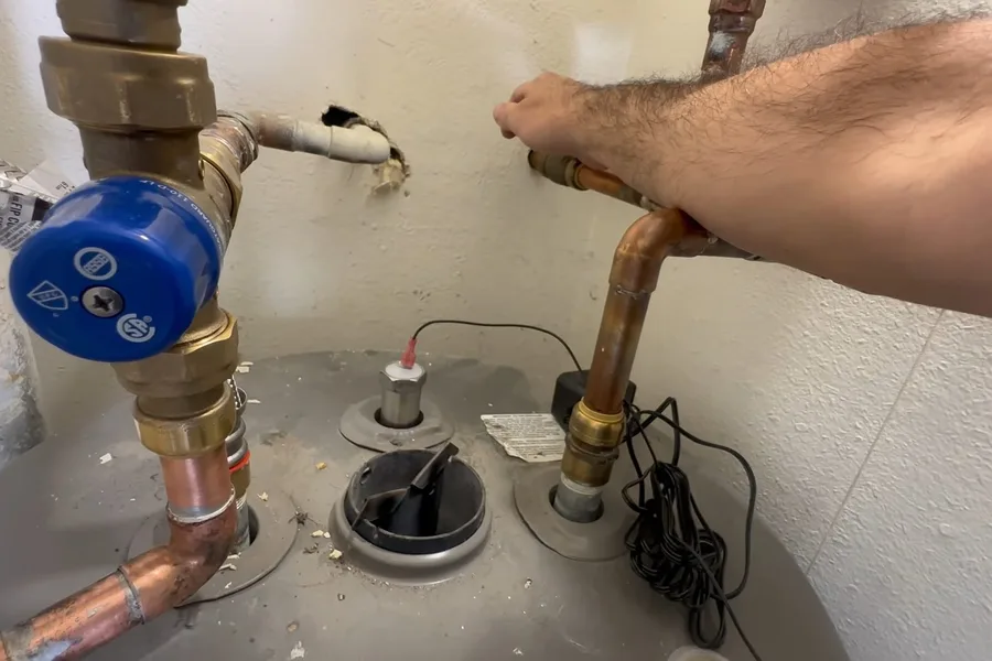 Plumber checking the top of a water heater tank illustrating your water heater's anode rod