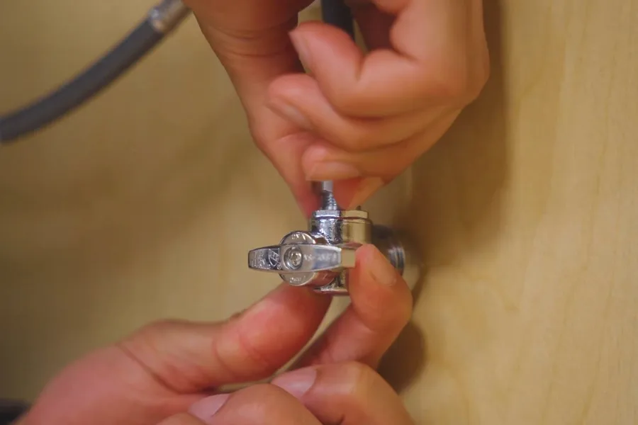 Hand tightening a shutoff valve below a sink for faucet & sink repair in Fountain Hills