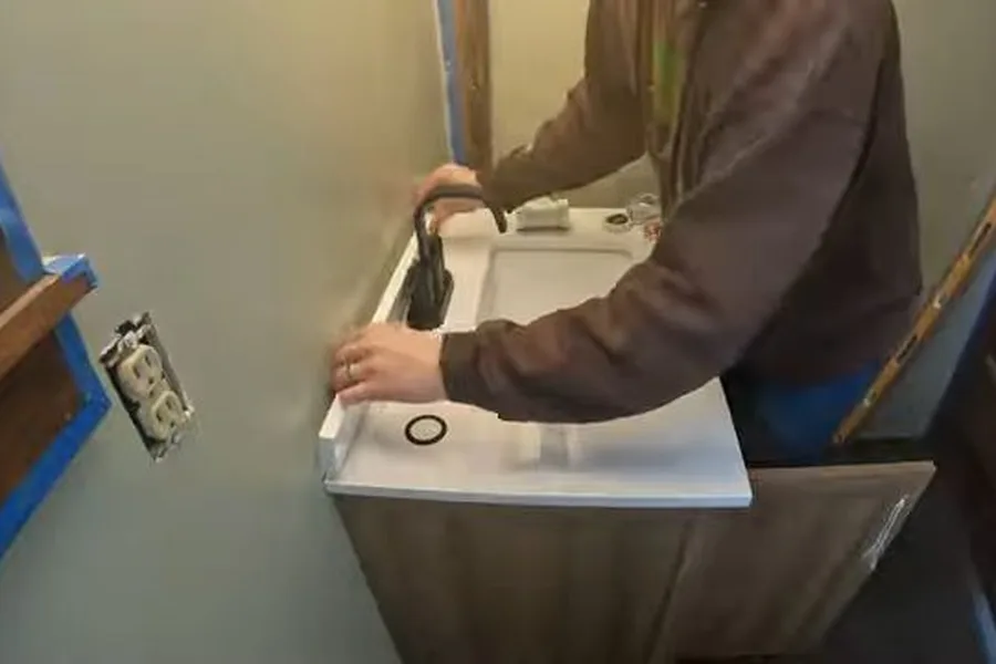 Plumber installing a small vanity drain during a plumbing service call in Palisades Park Area, Fountain Hills, AZ