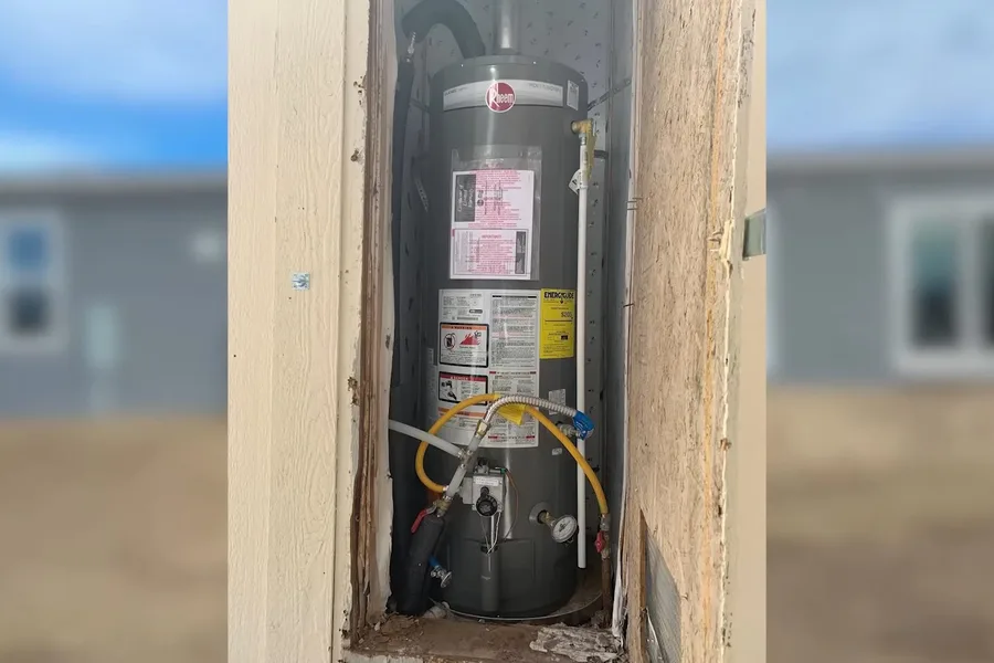 Open wall with water heater pipes and shutoffs illustrating a snowbird's pre-departure plumbing checklist for your fountain hills home