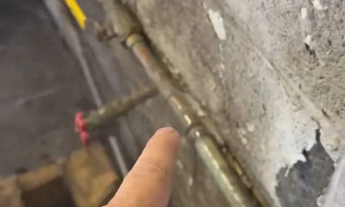 Plumber pointing at an exposed copper water line during a plumbing service call in Scottsdale, AZ