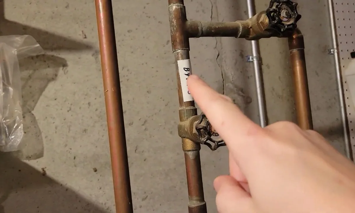 Plumber pointing at a water heater supply line during a plumbing service call in Gilbert, AZ
