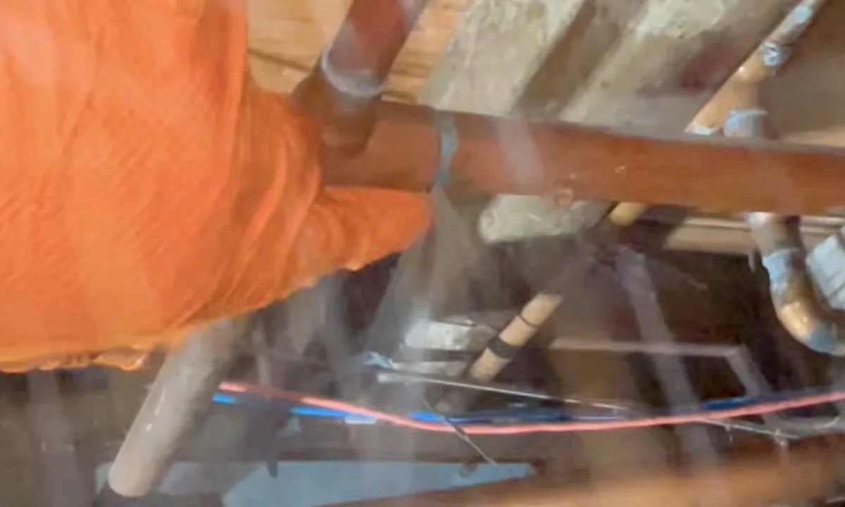 Technician entering a tight exterior access space during a plumbing service call in Gold Canyon, AZ