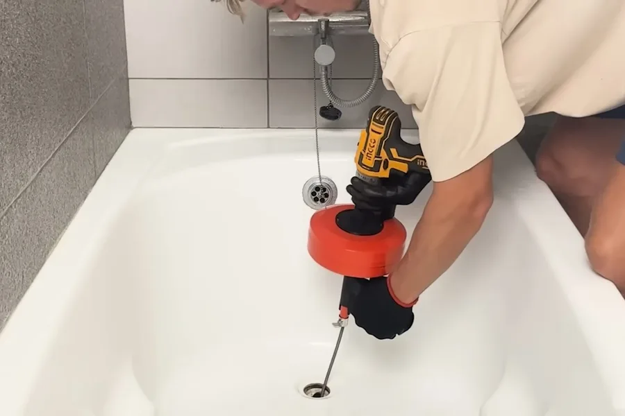 Plumber using a drain auger inside a bathtub during a plumbing service call in Cave Creek, AZ